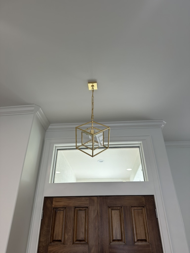 Gold cube lantern hung in the foyer above walnut double entry doors and a transom window