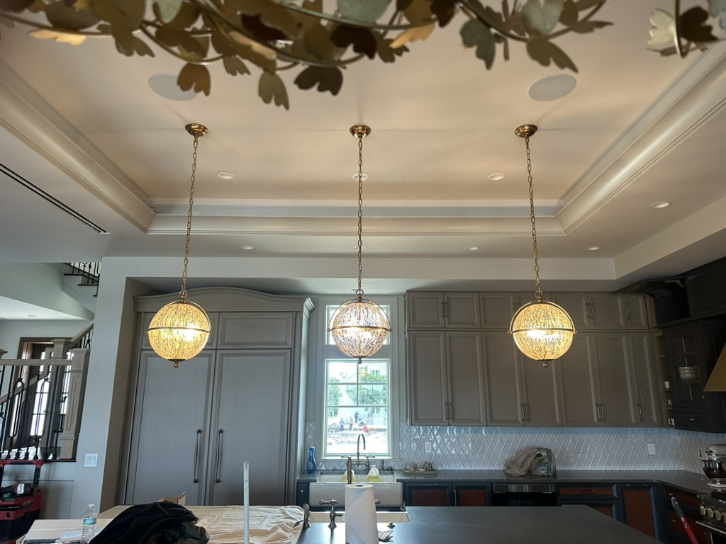 Three globe pendants centered on the kitchen island, looking toward the window and pantry wall