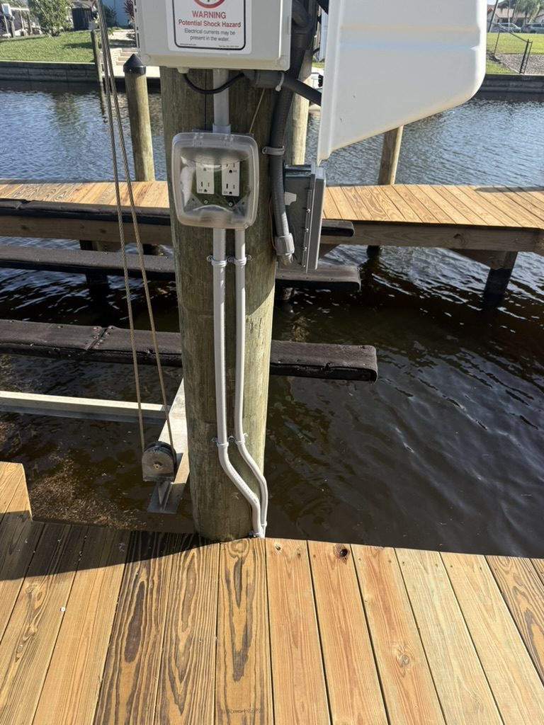 Two weatherproof receptacles in a clear cover with conduit running down the dock piling
