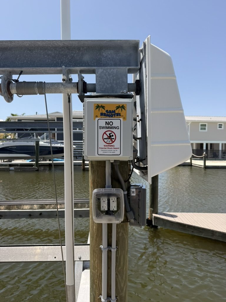 GEM Remotes control with a No Swimming sign, two outlets under a clear cover, the disconnect and the lift motor cover on a Fort Myers Beach dock