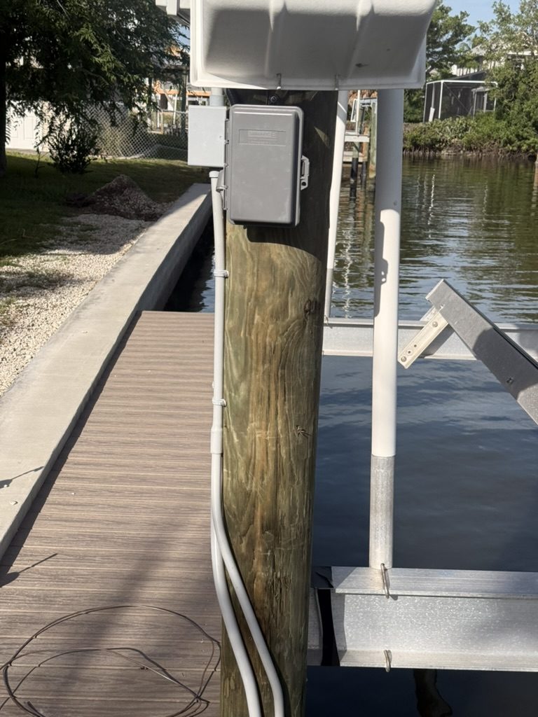 Weather-rated Square D disconnect and conduit on a piling beside the lift motor cover