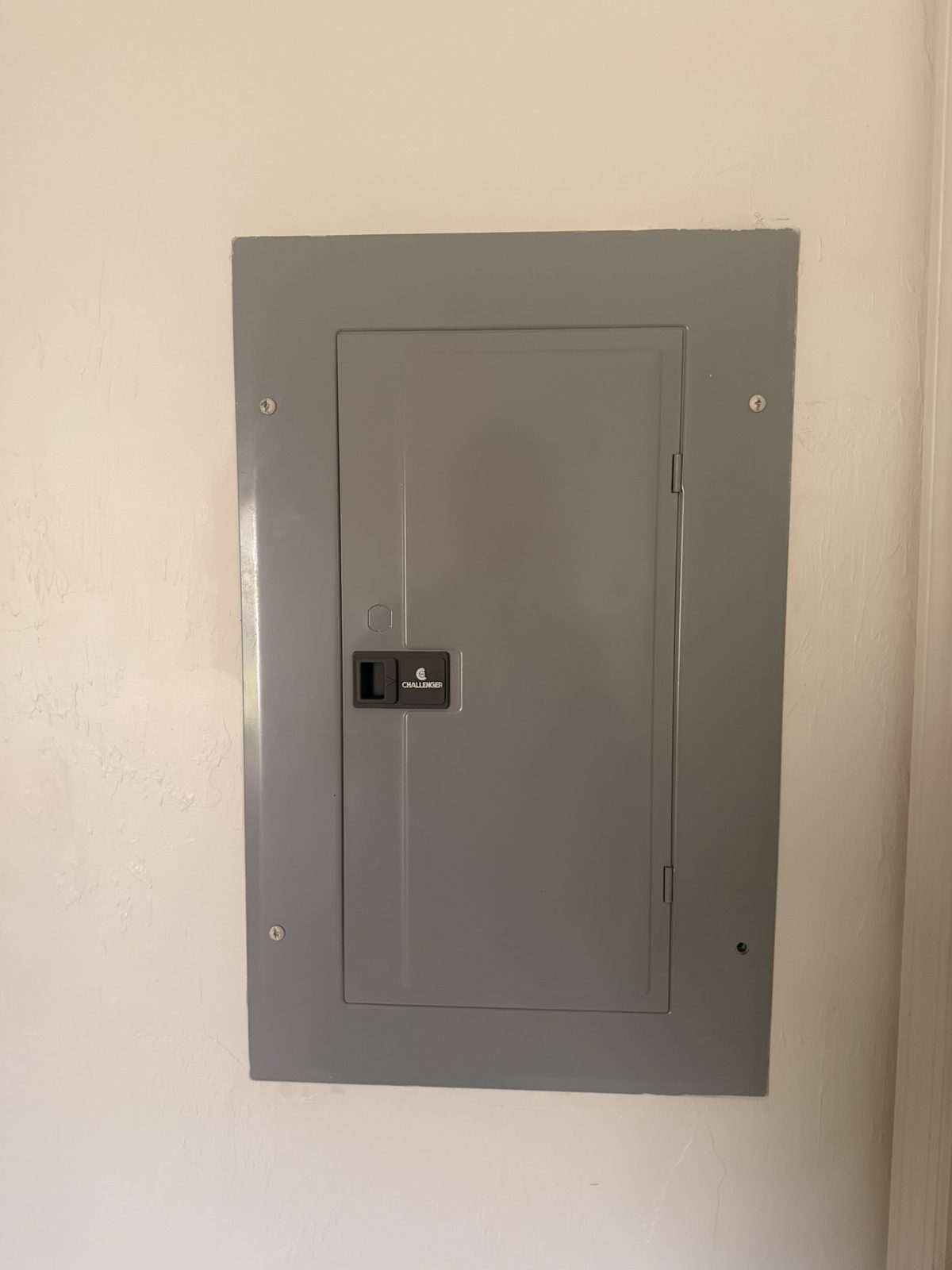 Challenger electrical panel cover on an interior wall, with the Challenger name on the latch