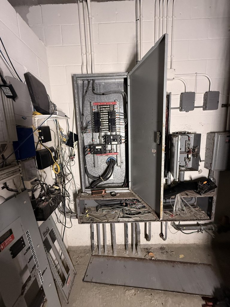 Flood-damaged 400-amp service equipment, panelboard, disconnects and wiring before replacement