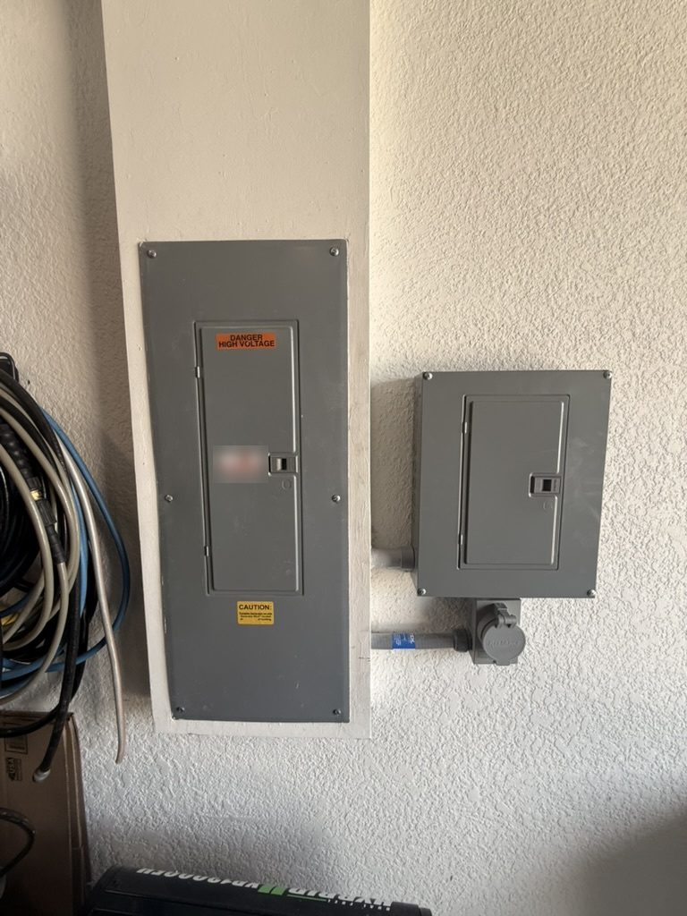Wide view of the new sub panel beside the existing larger panel on a Cape Coral home