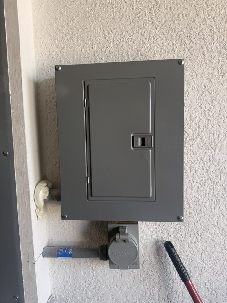 New sub panel with its door closed, above the existing generator inlet box