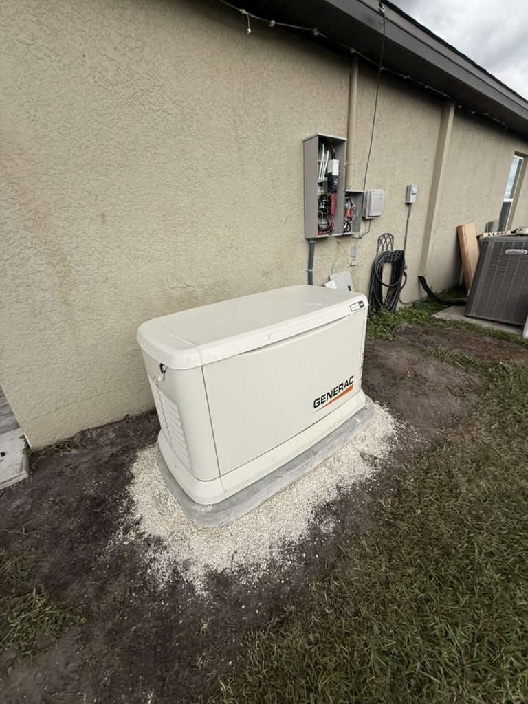 Generac generator on the concrete pad with gravel around it, and the transfer switch on the wall behind it
