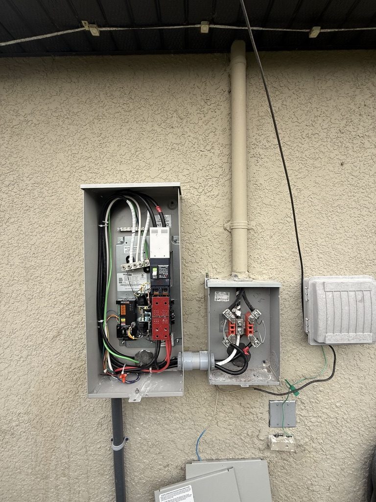 Generac automatic transfer switch with the cover off, showing the wiring, beside the adjacent service equipment