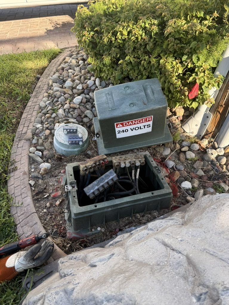 Utility company handhole where the service lines connect, beside a DANGER 240 VOLTS pedestal (utility equipment)