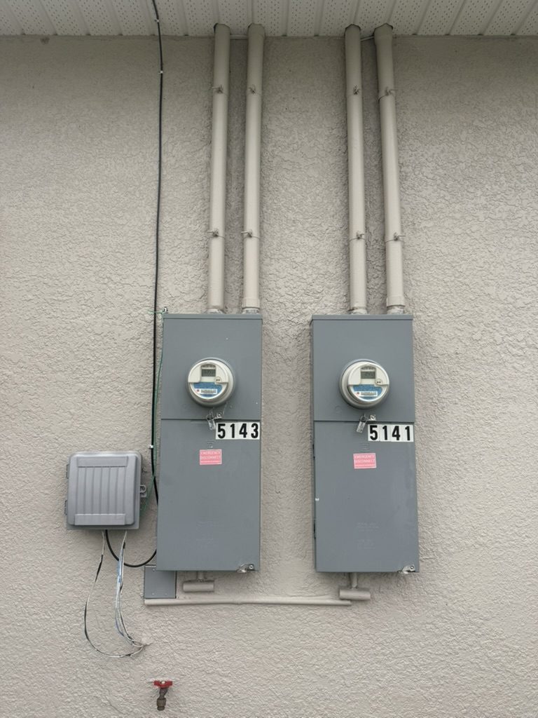The duplex’s two existing electric meters on the exterior wall before the work