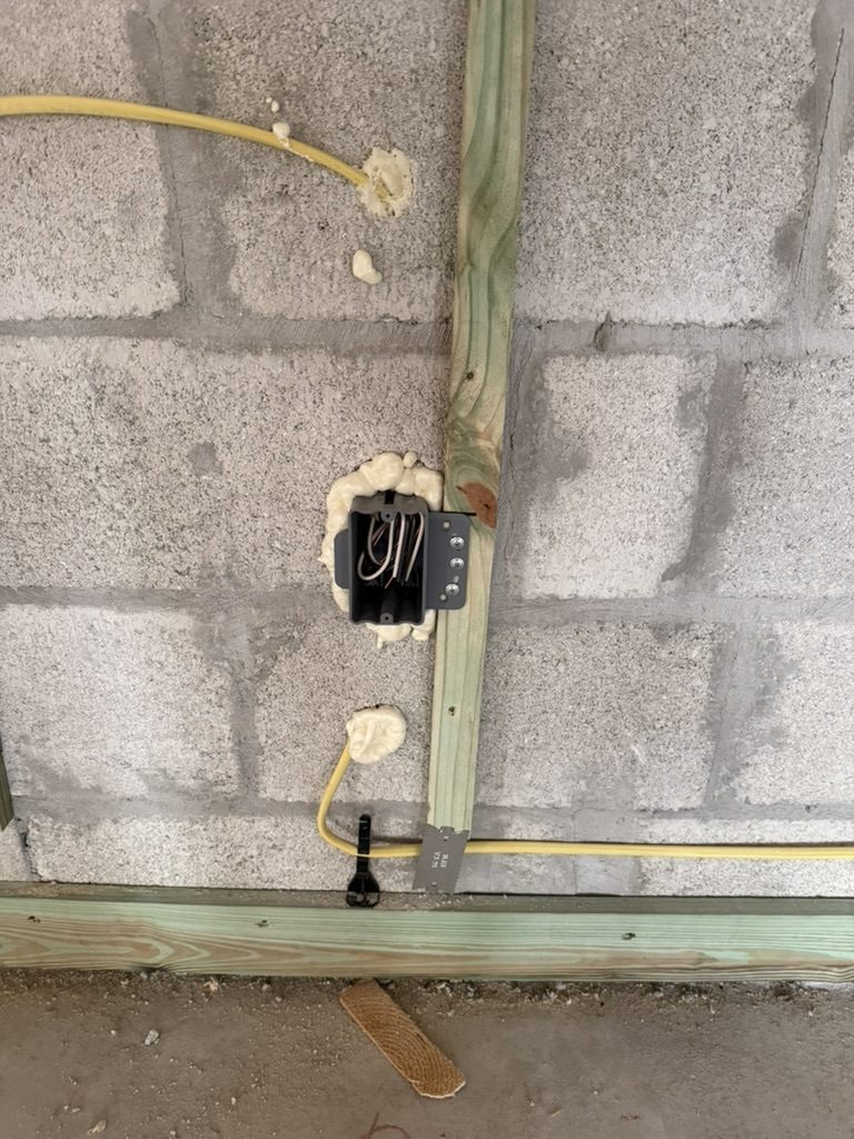 Device box and cable in the block wall, secured with a cable tie and foam