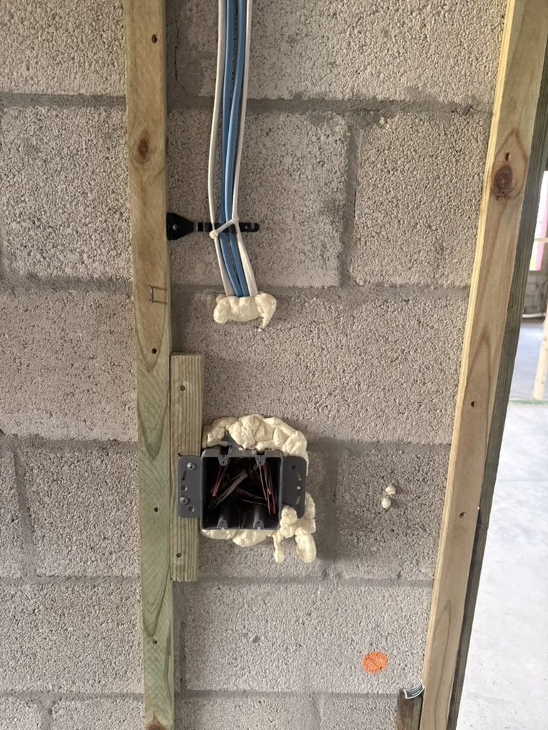 Device box and cables on a block wall, strapped and set with foam