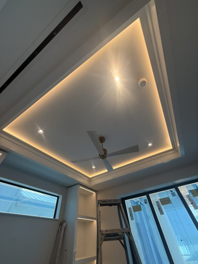 LED tape ceiling cove with recessed lights and a ceiling fan above built-in shelving