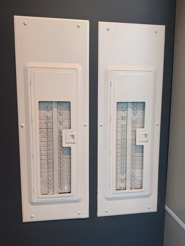 Two white Leviton electrical panels with glass fronts, side by side on a wall